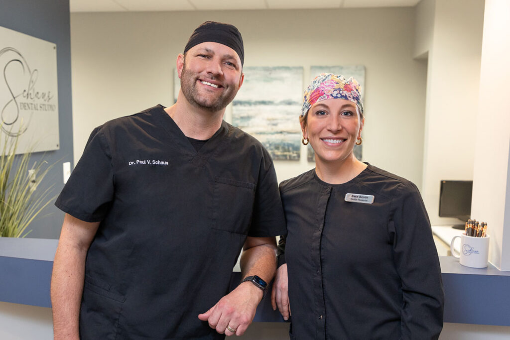 Dr. Paul Schaus and Sara standing at the reception are of the dental office